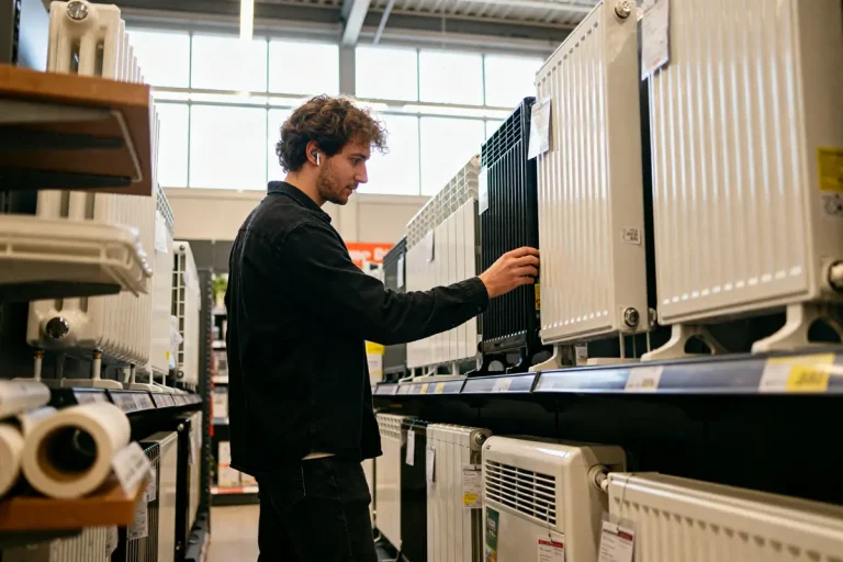 Homme examinant des radiateurs en magasin pour choisir un chauffage adapté à ses besoins
