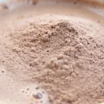 Poudre de chocolat dans une boisson chaude, formant une légère mousse.