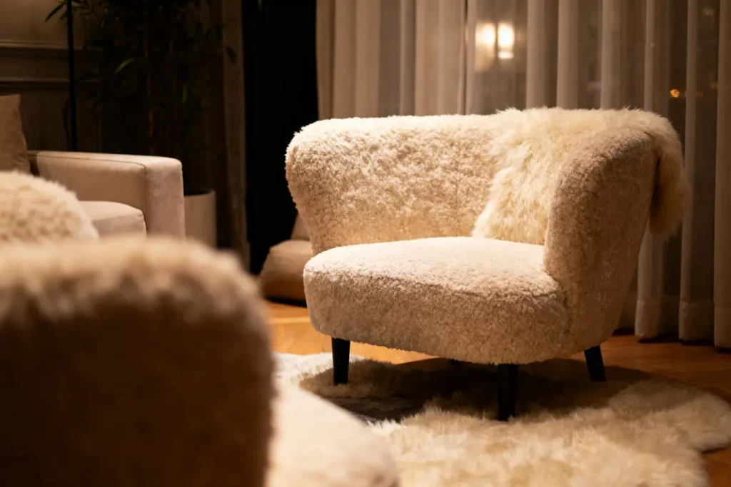Fauteuil en tissu pelucheux blanc dans un salon chaleureux avec tapis assorti, ambiance cosy.