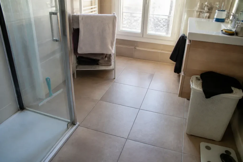 Salle de bain moderne avec carrelage beige au sol et douche vitrée élégante