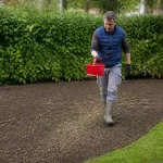 Homme semant du gazon dans un jardin vert pour savoir quand semer du gazon